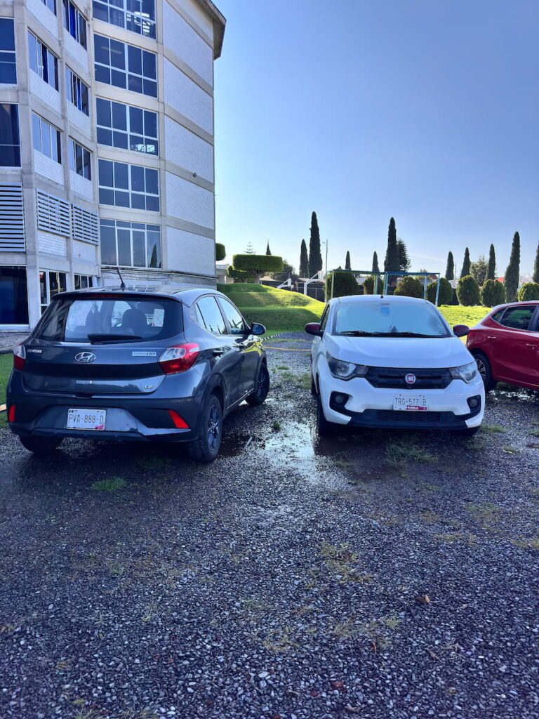 Llantas de automóviles parcialmente sumergidas en charcos dentro del estacionamiento de la Universidad Madero.