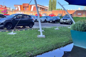 Vista general del estacionamiento de la UMAD cubierto de charcos y con el suelo de grava deteriorado por las lluvias.