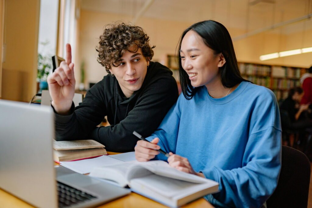 Dos jóvenes universitarios sonríen y celebran juntos al finalizar su semana de exámenes.