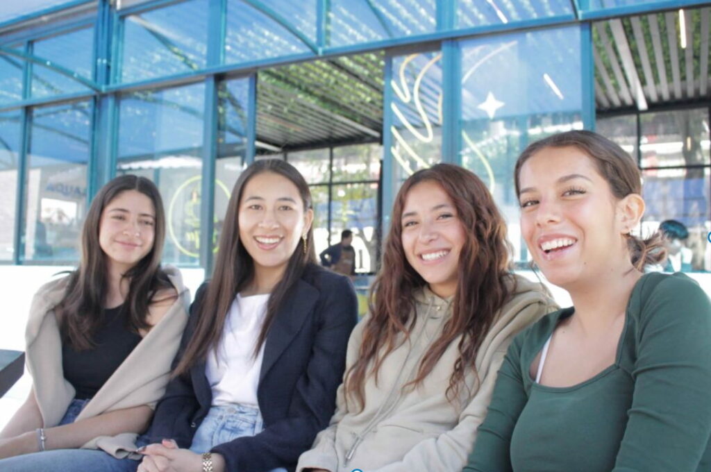 Cuatro estudiantes sentadas en un área exterior del campus UMAD, zona de convivencia y movilidad estudiantil.