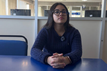 Jessica González sentada frente a una mesa azul durante una entrevista, exponiendo ideas sobre cómo fortalecer seguridad en la UMAD.
