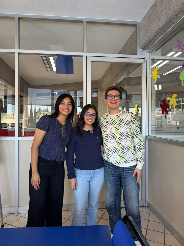 Jessica González al centro, junto a un reportero y reportera posando en un área interior de la UMAD.